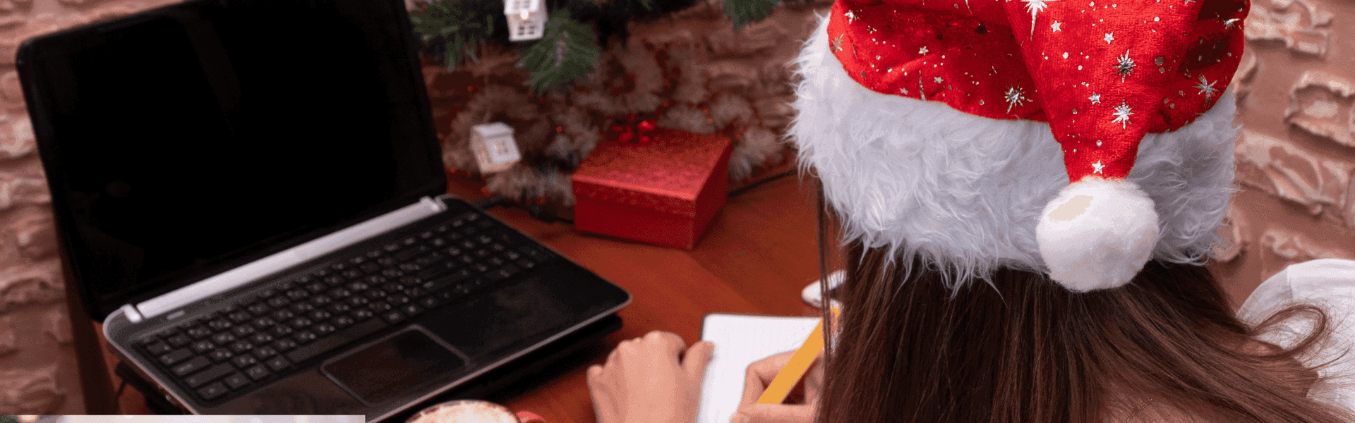 Frau mit Nikolausmütze sitzt vor dem PC und schreibt 