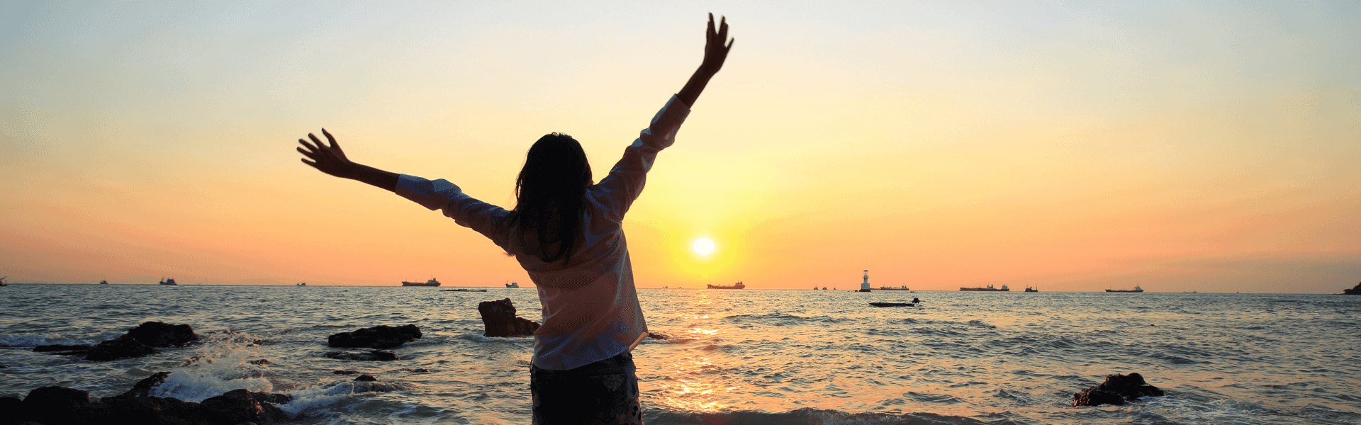 Hitzefrei – Frau genießt den Sonnenuntergang am Meer. Tipps für den Umgang mit hohen Temperaturen im Büro und flexible Arbeitszeiten an heißen Tagen.